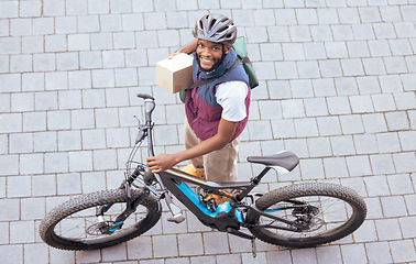 Image showing Black man, delivery bike and street portrait from top view for logistics, cargo and happy for job. Young african person, bicycle and shipping service with box package, helmet and safety in metro