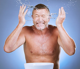 Image showing Skincare, senior man and water splash with basin, dermatology and guy with blue studio background. Face detox, mature male and old gentleman with clear liquid, hygiene or aqua for freshness with bowl