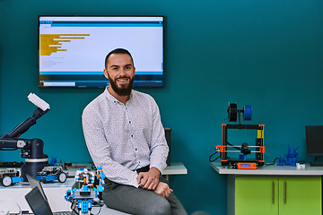 Image showing A bearded man in a modern robotics laboratory, immersed in research and surrounded by advanced technology and equipment.