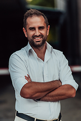 Image showing A successful businessman in a white shirt with crossed arms posing outdoors