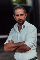 Image showing A successful businessman in a white shirt with crossed arms posing outdoors