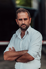 Image showing A successful businessman in a white shirt with crossed arms posing outdoors