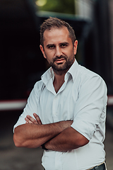 Image showing A successful businessman in a white shirt with crossed arms posing outdoors