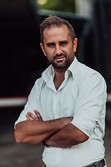 Image showing A successful businessman in a white shirt with crossed arms posing outdoors