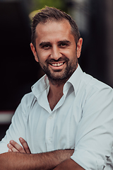 Image showing A successful businessman in a white shirt with crossed arms posing outdoors