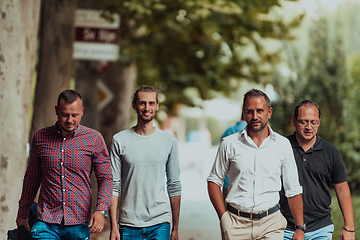 Image showing After a productive day at work, a group of diverse colleagues enjoy a leisurely stroll through a modern and natural urban setting