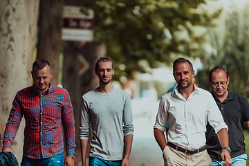 Image showing After a productive day at work, a group of diverse colleagues enjoy a leisurely stroll through a modern and natural urban setting