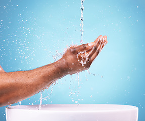 Image showing Closeup, hands and water splash for cleaning, basin and dermatology against blue studio background. Zoom, man and washing with bowl, wellness and morning routine or grooming, skincare and backdrop