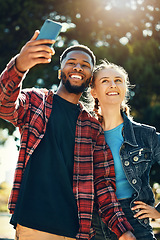 Image showing Selfie, love and happy couple on an outdoor date for their anniversary or romance together. Happiness, smile and interracial man and woman taking picture on a phone while on a walk in park in nature.