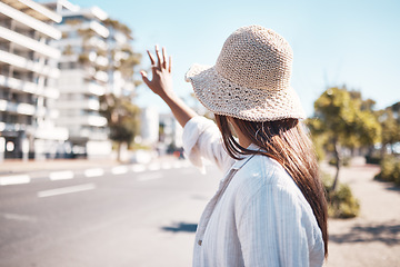 Image showing Woman, city and street to stop taxi, travel and transportation in summer, holiday and outdoor urban adventure. Girl, back and hand sign for transport in metro, road or cbd for vacation in sunshine