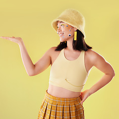 Image showing Fashion, hand and Asian woman with comic eyes isolated on a yellow background in a studio. Happy, funny and stylish girl model with mockup for product placement space, advertising and motivation