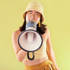 Image showing Asian, woman and studio with megaphone for protest, speech and activism for human rights by background. Young gen z model, loudspeaker broadcast and yellow 90s aesthetic for change, justice and voice
