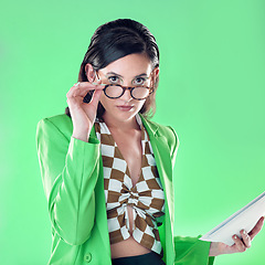 Image showing Fashion, teacher and portrait of a woman in studio with glasses and paperwork to read. Style, trendy and female educator or model with stylish, cool and edgy outfit and spectacles by green background