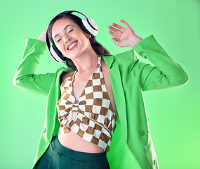 Image showing Music, fashion and woman dance on green background with trendy, stylish clothes and cosmetics in studio. Disco aesthetic, headphones and happy girl relax, dancing and streaming song, audio and radio
