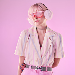 Image showing Fashion, glasses and woman on pink background for beauty, vaporwave style and cosmetics in studio. Creative aesthetic, makeup and female model with earmuffs, trendy clothes and cyberpunk accessories