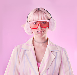 Image showing Fashion, quirky and portrait of woman in studio for funny or comic face on pink background. Aesthetic model person with glasses and earmuffs for edgy vaporwave trend with creativity, humour and color