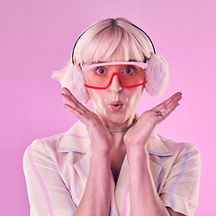 Image showing Fashion, portrait and a woman quirky in studio for wow, surprise and comic face on pink background. Aesthetic model person with glasses and earmuffs for edgy vaporwave trend with creativity and color