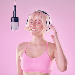 Image showing Headphones, microphone and woman singer in a studio recording a song, album or music. Happy, passion and young female artist or musician singing with equipment while isolated by a pink background.