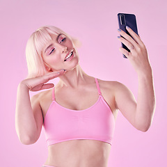 Image showing Selfie, beauty and woman in a studio with a makeup or cosmetic face routine with a cellphone. Cosmetics, style and female model from Australia taking a picture on a phone isolated by pink background.