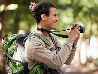 Image showing Photography man, camera and outdoor park with smile, focus or adventure with creative vision. Young nature journalist, expert photographer and bird watching with tech, hiking or backpack for research