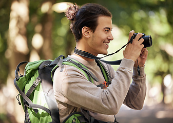 Image showing Photographer man, camera and outdoor park with smile, focus or adventure with creative vision. Young nature journalist, photography expert and bird watching with tech, hiking or backpack for research