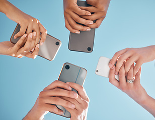 Image showing Hands, phone and people networking below on social media or mobile app with blue sky background. Low angle hand of group with smartphone in circle for online share, data sync or team communication