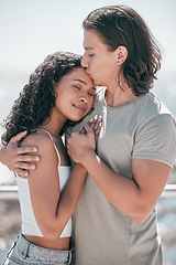 Image showing Love, kiss and couple hug at beach, happy and outdoor for travel, romance and bond on blurred background. Forehead, kisses and man embracing woman, sweet and romantic, relation and traveling together