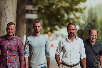 Image showing After a productive day at work, a group of diverse colleagues enjoy a leisurely stroll through a modern and natural urban setting