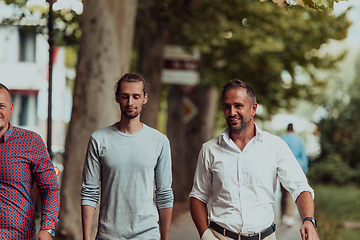 Image showing After a productive day at work, a group of diverse colleagues enjoy a leisurely stroll through a modern and natural urban setting