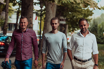 Image showing After a productive day at work, a group of diverse colleagues enjoy a leisurely stroll through a modern and natural urban setting