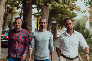 Image showing After a productive day at work, a group of diverse colleagues enjoy a leisurely stroll through a modern and natural urban setting