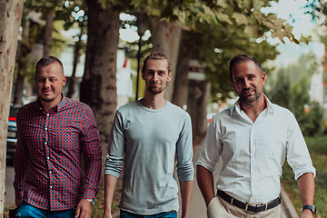 Image showing After a productive day at work, a group of diverse colleagues enjoy a leisurely stroll through a modern and natural urban setting