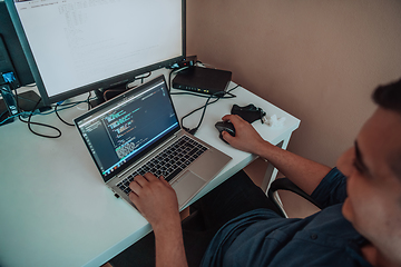 Image showing A programmer diligently testing smartphone applications while sitting in their office.