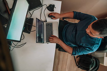 Image showing Top view of programmer diligently testing smartphone applications while sitting in their office.