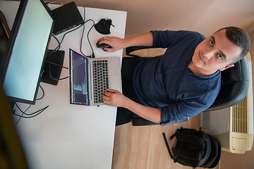 Image showing Top view of programmer diligently testing smartphone applications while sitting in their office.