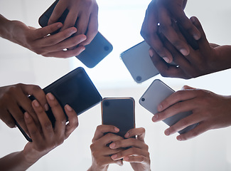 Image showing Hands, phone and people networking below on social media, mobile app or chatting together. Low angle hand of group with smartphone in circle for online network share, data sync or team communication