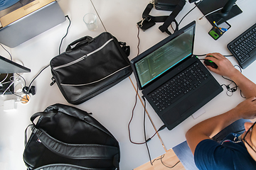 Image showing Top view of programmer diligently testing smartphone applications while sitting in their office.