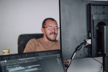 Image showing A programmer diligently testing smartphone applications while sitting in their office.