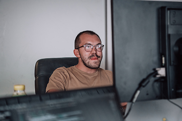 Image showing A programmer diligently testing smartphone applications while sitting in their office.