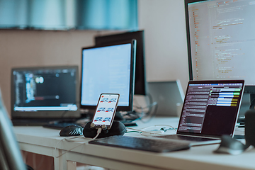 Image showing Computer screens running programming code in empty software developing agency office and computers parsing data algorithms in background. Neural network servers cloud computing in data room.