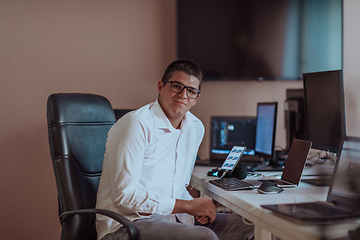 Image showing A programmer diligently testing smartphone applications while sitting in their office.