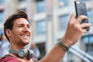 Image showing Selfie, man and smile in the city for travel profile picture, social media and influencer streaming. Happiness, vacation and young person online with headphones and memories outdoor on holiday