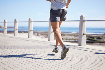 Image showing Fitness, sports and legs of man running by ocean for wellness, performance and athlete endurance. Nature, motivation and feet of male runner by sea for exercise, marathon training and cardio workout