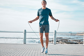 Image showing Jump rope, happy and man workout by the beach for his outdoor morning exercise, training and fitness routine. Athlete, cardio and male skipping by the ocean or sea for wellness lifestyle