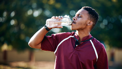 Image showing Rugby, sports or black man drinking water in training, exercise or workout match on a field. Fitness, thirsty or tired African athlete drinks liquid in a bottle for energy or hydration in summer