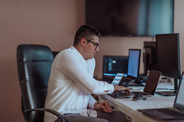 Image showing A programmer diligently testing smartphone applications while sitting in their office.