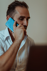 Image showing A businessman talking on his smartphone while seated in an office, showcasing his professional demeanor and active communication.