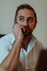 Image showing A businessman talking on his smartphone while seated in an office, showcasing his professional demeanor and active communication.