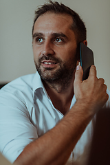 Image showing A businessman talking on his smartphone while seated in an office, showcasing his professional demeanor and active communication.