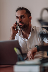 Image showing A businessman talking on his smartphone while seated in an office, showcasing his professional demeanor and active communication.